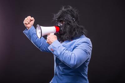 businessman wearing gorilla mask and screaming to megafon-stock-photo