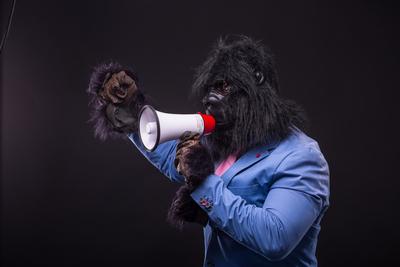 businessman wearing gorilla mask and screaming to megafon-stock-photo