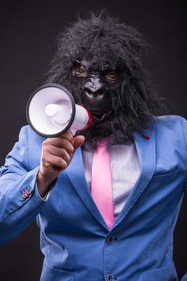 businessman wearing gorilla mask and screaming to megafon-stock-photo