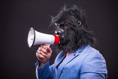 businessman wearing gorilla mask and screaming to megafon-stock-photo