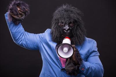 businessman wearing gorilla mask and screaming to megafon-stock-photo