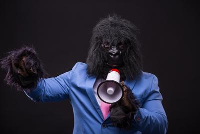 businessman wearing gorilla mask and screaming to megafon-stock-photo