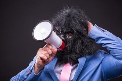 businessman wearing gorilla mask and screaming to megafon-stock-photo