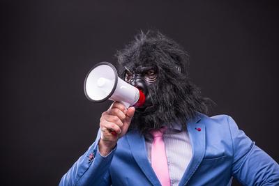 businessman wearing gorilla mask and screaming to megafon-stock-photo