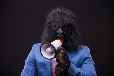 businessman wearing gorilla mask and screaming to megafon-stock-photo