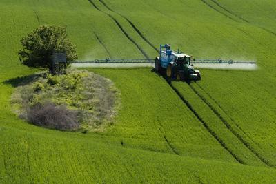 A farmer spraying on the spring wheat field with a John Deere tractor and a mamut topline sprayer.-stock-photo