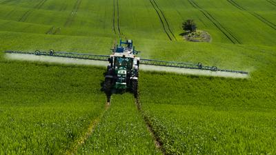 A farmer spraying on the spring wheat field with a John Deere tractor and a mamut topline sprayer.-stock-photo